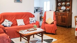 Una sala de estar con un sofá rojo, una mesa de centro de madera y un comedor con un aparador de madera y platos.