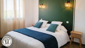 Ein Schlafzimmer mit einem Bett, zwei Nachttischen, einem Fenster mit Vorhängen und Wandleuchten.