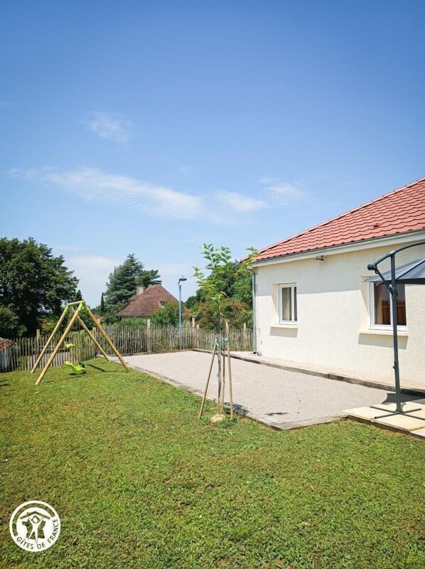 A residential area with a white house, a swing set, and a paved driveway.