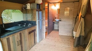 Eine kleine Küche mit Holzausstattung, einem Edelstahlkühlschrank, einer Mikrowelle und einem Gasherd.