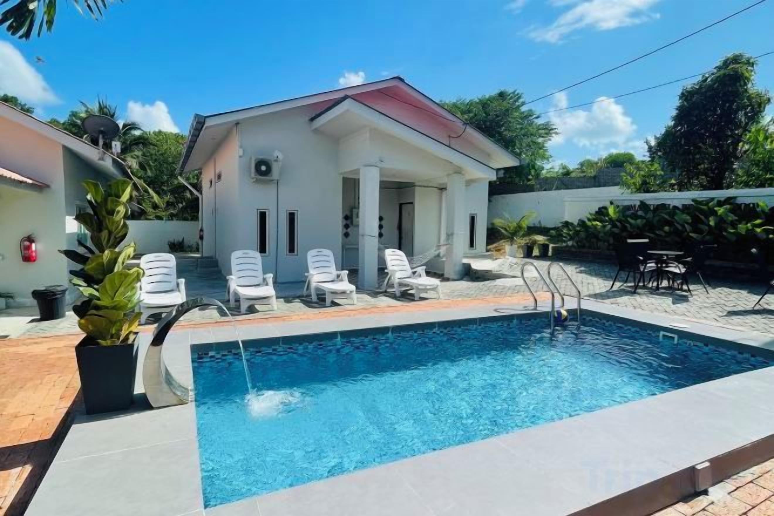 A swimming pool with lounge chairs and a small building with a red roof.