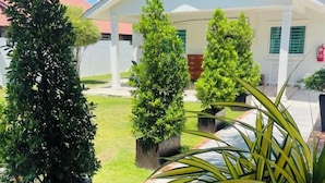 A courtyard with potted plants and a building with a white facade and green shutters. - Rooma Kichi Private Pool (Langkawi)