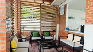 A private room with a brick wall, wooden blinds, and a seating area with chairs and a small table. - Rooma Kichi Private Pool (Langkawi)