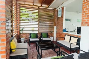 Un petit espace extérieur aménagé, à l’abri, avec un mur en briques, des stores en bois et un coin cuisine.