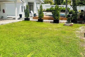 A well-maintained lawn with potted plants, a pool area, and a white building with a sign that reads "Infinity Pool". - Rooma Kichi Private Pool (Langkawi)