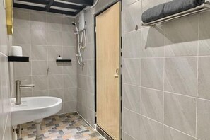 A small bathroom with a sink, shower, and a towel rack.