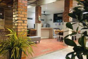A modern interior with a brick column, a ceiling fan, and a dining area with chairs and a table. - Rooma Kichi Private Pool (Langkawi)