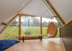 A modern room with a large window, a hanging chair, and a bench.