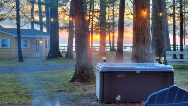 A hot tub in a forested area with a view of the sunset. - Scenic Drive Resort - Cabin #1 (Muskegon)