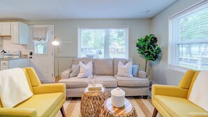 A living room with a sofa, two yellow armchairs, a coffee table, and a plant. - Scenic Drive Resort - Cabin #1 (Muskegon)