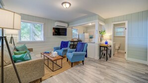 Un salon confortable avec un canapé, deux fauteuils, une table basse et un téléviseur.