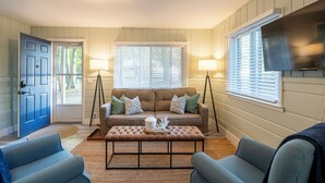 Un salon avec un canapé marron, deux lampadaires, une table basse et une porte bleue.
