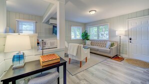 A living room with a sofa, a table with a chessboard, a lamp, and a large mirror. - Scenic Drive Resort - Cabin #7 (Muskegon)