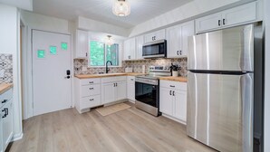 Een moderne keuken met witte kasten, roestvrijstalen apparatuur en een houten aanrecht.