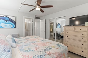 Ein Schlafzimmer mit Bett, Deckenventilator, Kommode, Fernseher und einem Gemälde an der Wand.