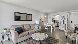 A modern living room with a sofa, coffee table, and dining area.