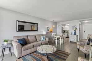 A modern living room with a sofa, coffee table, and dining area.