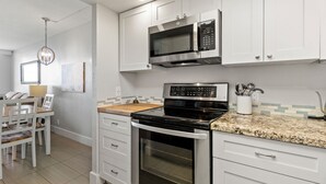 Une cuisine moderne avec des meubles blancs, un four à micro-ondes encastré, une cuisinière et un coin repas comprenant une table et des chaises.