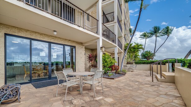 Un immeuble à plusieurs étages doté d’un patio aménagé avec du mobilier d’extérieur et offrant une vue sur l’océan.