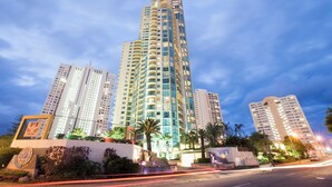 A high-rise building with multiple balconies, surrounded by palm trees and other greenery. - Mantra Sun City Surfers Paradise (Gold Coast)