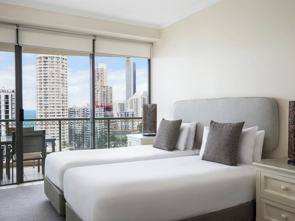 Una habitación de hotel con dos camas, un balcón y vistas a la ciudad.