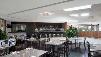 A modern restaurant with high ceilings, a bar area, and seating for guests.