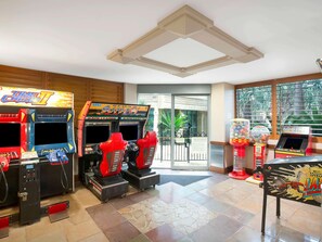 A room with arcade games, a large window, and a door leading outside. - Mantra Sun City Surfers Paradise (Gold Coast)
