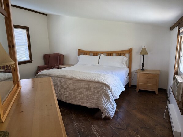 A bedroom with a wooden bed, a nightstand, a chair, and a dresser.