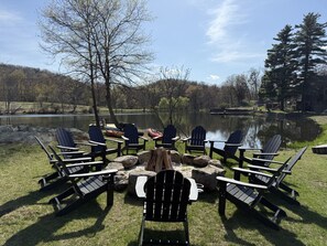 A lakeside seating area with Adirondack chairs arranged around a central fire pit. - Red Cottage - Lakeside Property! (Fishkill)