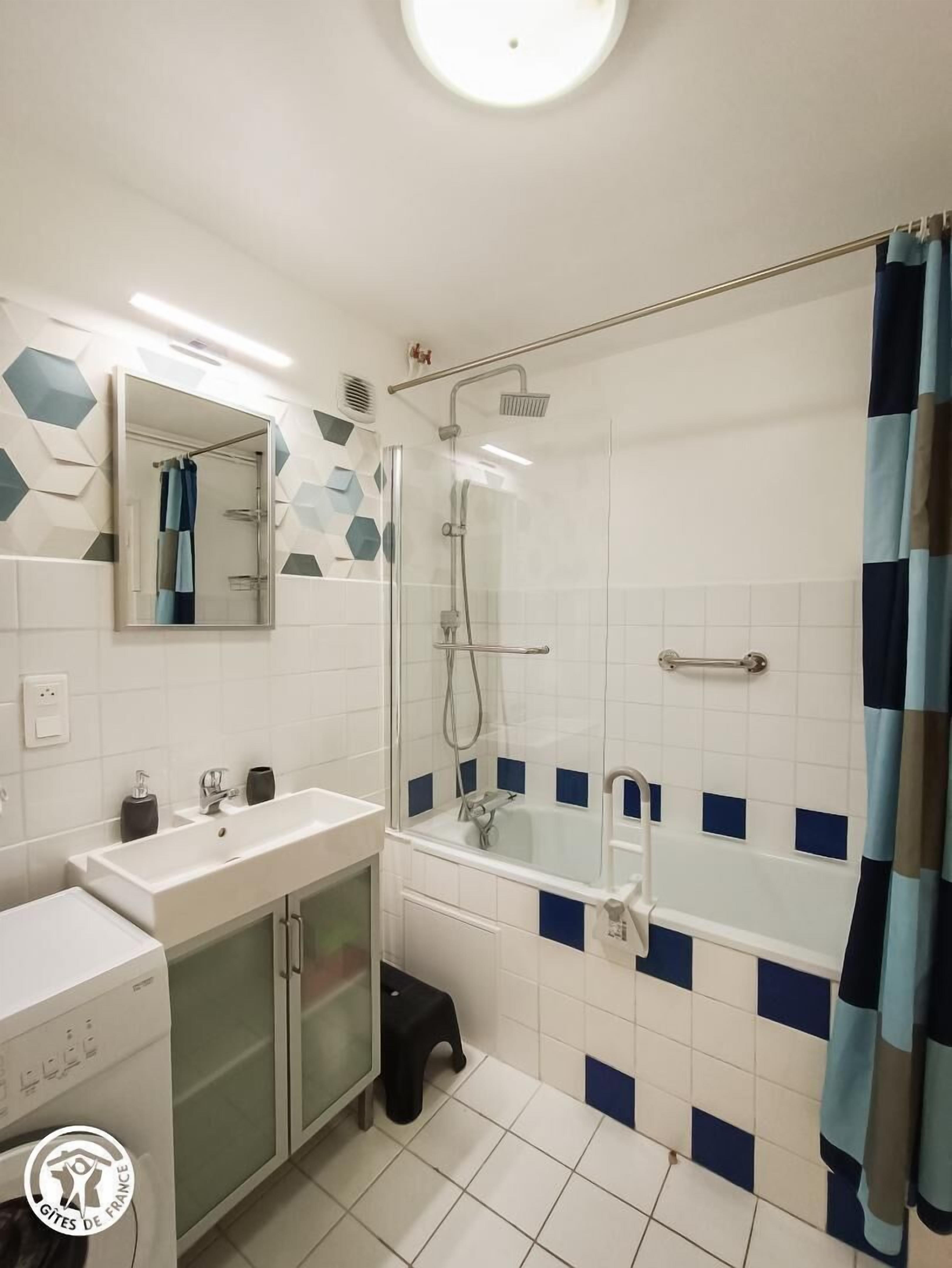 A modern bathroom with a glass-enclosed shower, a white sink with a cabinet, and a mirror above the sink.