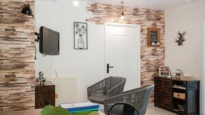Et moderne spiseområde med et træbord, stole og et fjernsyn ophængt på væggen.