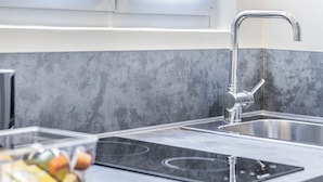 A modern kitchen with a stainless steel sink, a built-in stovetop, and a grey textured backsplash.