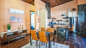 A modern kitchen with wooden cabinets, a stainless steel refrigerator, and a dining area with a wooden table and orange chairs. - New, Amazing, Cozy, Jacuzzi, Mountain Views, Minutes 2 Downtown, Snow Bowl (Flagstaff)