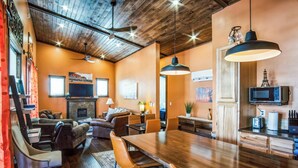 A modern living room with a fireplace, wooden ceiling, and a dining area with a large wooden table and chairs. - New, Amazing, Cozy, Jacuzzi, Mountain Views, Minutes 2 Downtown, Snow Bowl (Flagstaff)