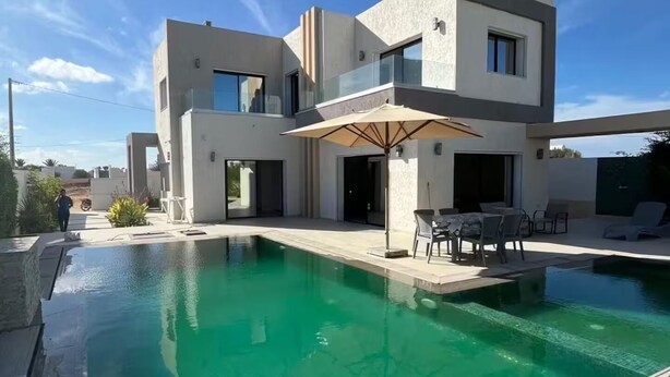 A modern two-story house with a swimming pool, outdoor furniture, and a clear blue sky. - Villa with pool in Djerba Tezdain sea view (midoun)