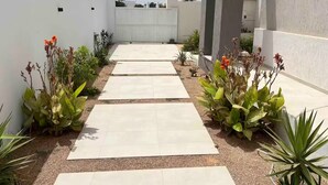A modern outdoor pathway with a gravel border and potted plants on either side. - Villa with pool in Djerba Tezdain sea view (midoun)