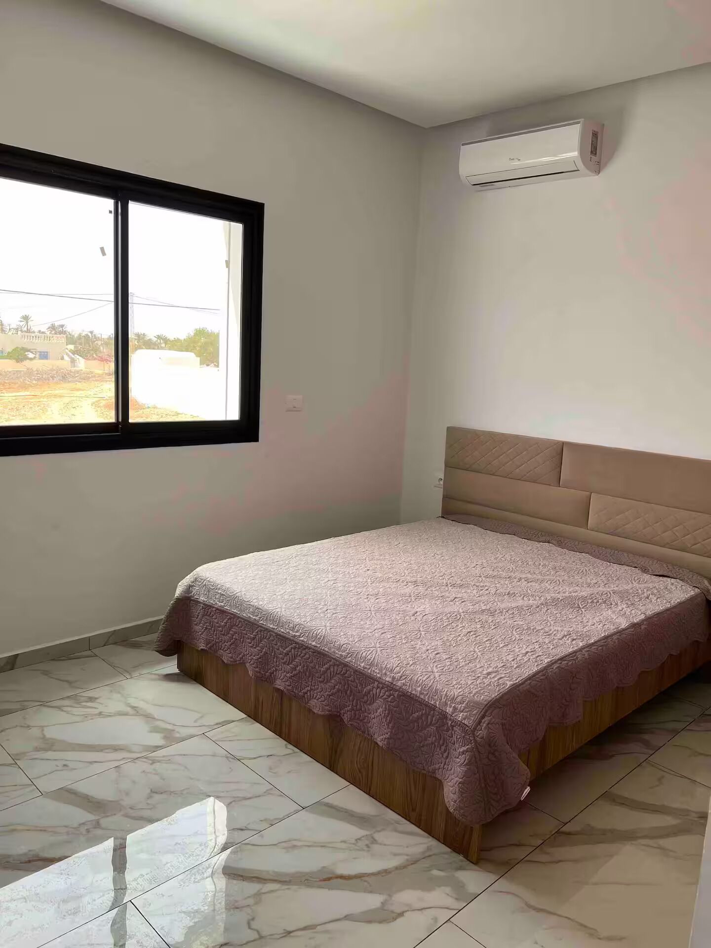 Quarto com cama, janela e ar condicionado.