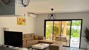 A modern living room with a sectional sofa, a flat-screen TV, a coffee table, and a glass dining table. - Villa with pool in Djerba Tezdain sea view (midoun)