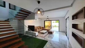 A modern interior with a staircase, a living area with a sofa and coffee table, and a large window offering a view. - Villa with pool in Djerba Tezdain sea view (midoun)