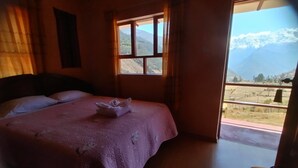 Un dormitorio con cama, ventana y vistas a montañas.