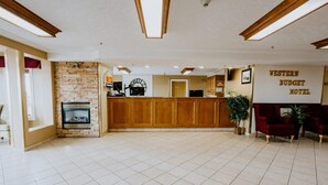 A reception area with a stone wall, wooden reception desk, and a sign reading "Western Budget Motel". - Western Budget Plus Grande Prairie 2 (Grande Prairie)