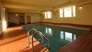An indoor swimming pool with a clear view of the pool area, a visible door, and a clock on the wall. - Western Budget Plus Grande Prairie 2 (Grande Prairie)