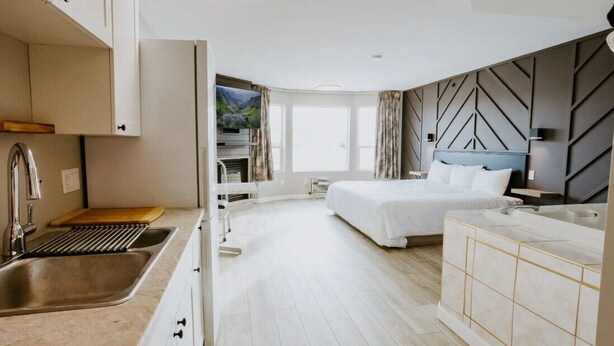 A modern hotel room with a kitchen area, a large bed, and a view of the outdoors. - Western Budget Plus Grande Prairie 2 (Grande Prairie)