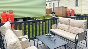 A deck with outdoor furniture, including a sofa and chairs, and two propane tanks. - This lovely caravan is perfect for couples, friends, or families. (Sandown)