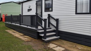 A mobile home with a black railing and steps leading to a door. - This lovely caravan is perfect for couples, friends, or families. (Sandown)