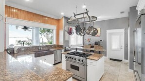 Una cocina moderna con encimeras de granito, electrodomésticos de acero inoxidable y un colgador para ollas.