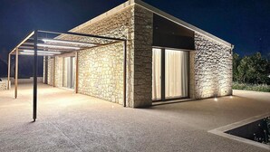 A modern building with stone walls and large windows, featuring a covered outdoor area with a pergola. - Cozy home in Chiaramonte Gulfi (Chiaramonte Gulfi)