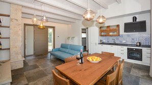 A modern kitchen with a dining area, stone walls, and a blue sofa. - Cozy home in Chiaramonte Gulfi (Chiaramonte Gulfi)