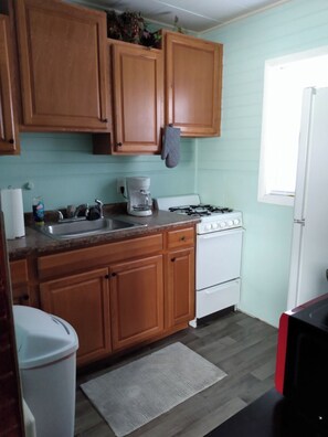 A kitchen with wooden cabinets, a gas stove, a sink, and a window. - 1 bed, 1 bath Central DM by VA Hospital North of Drake University No Stairs. (Des Moines)