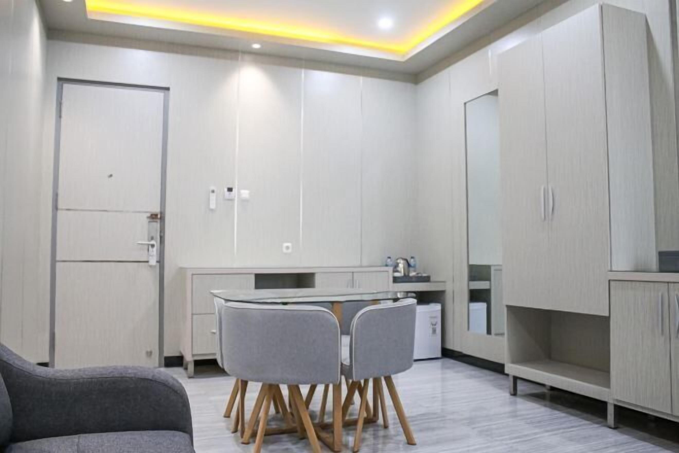 A modern kitchen with white cabinets, a dining table with four chairs, and a built-in oven.